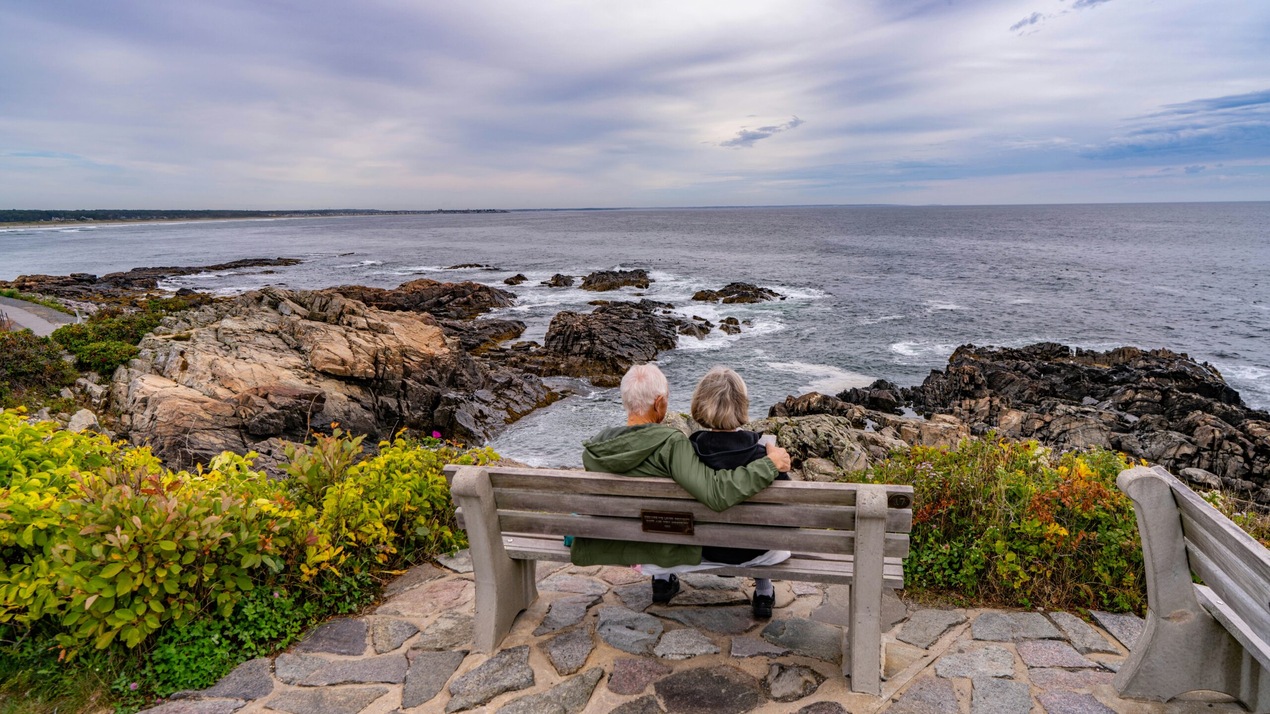 Person sitting on a bench overlooking the ocean thinking about retirement
