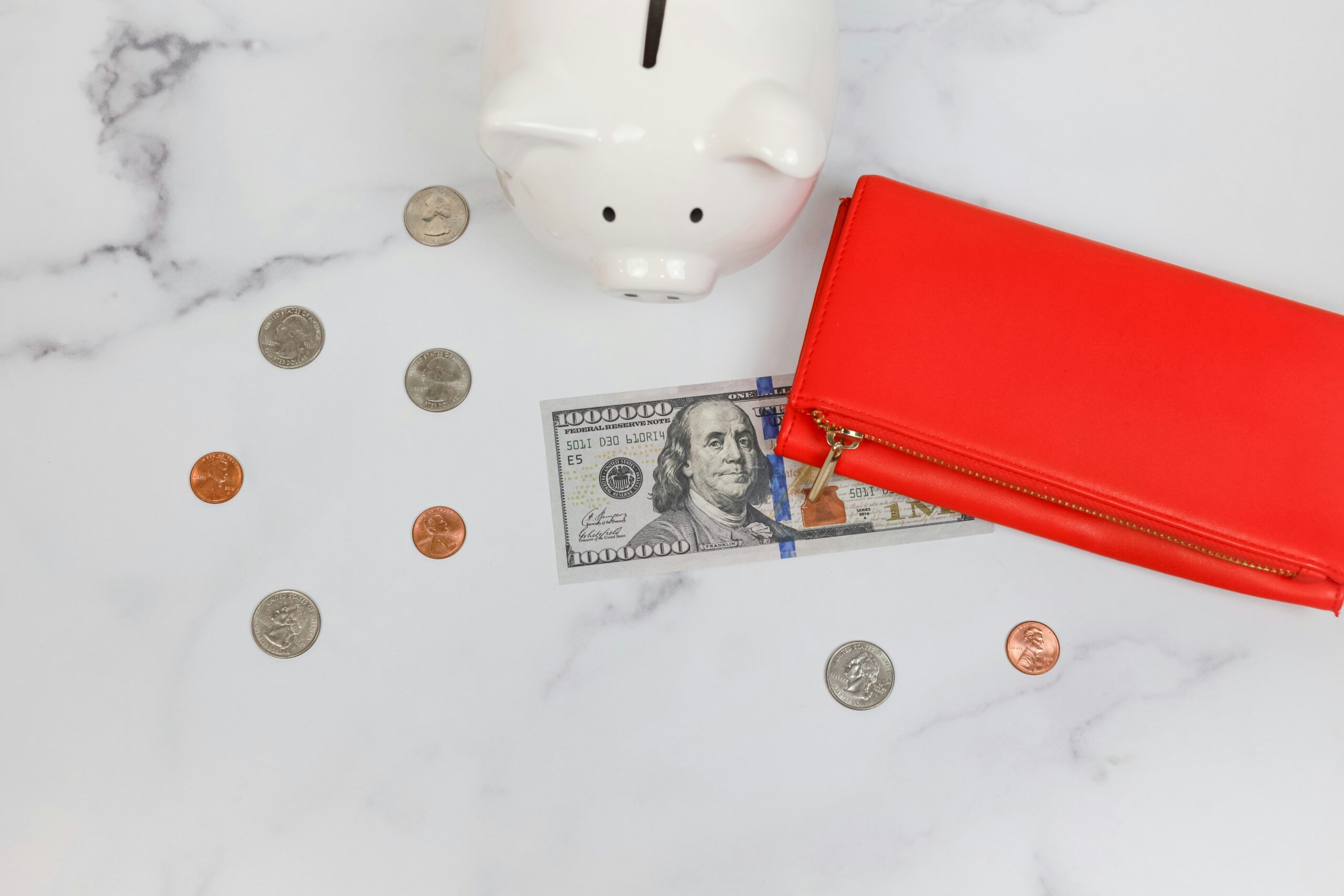 Coins falling near a piggy bank and red purse