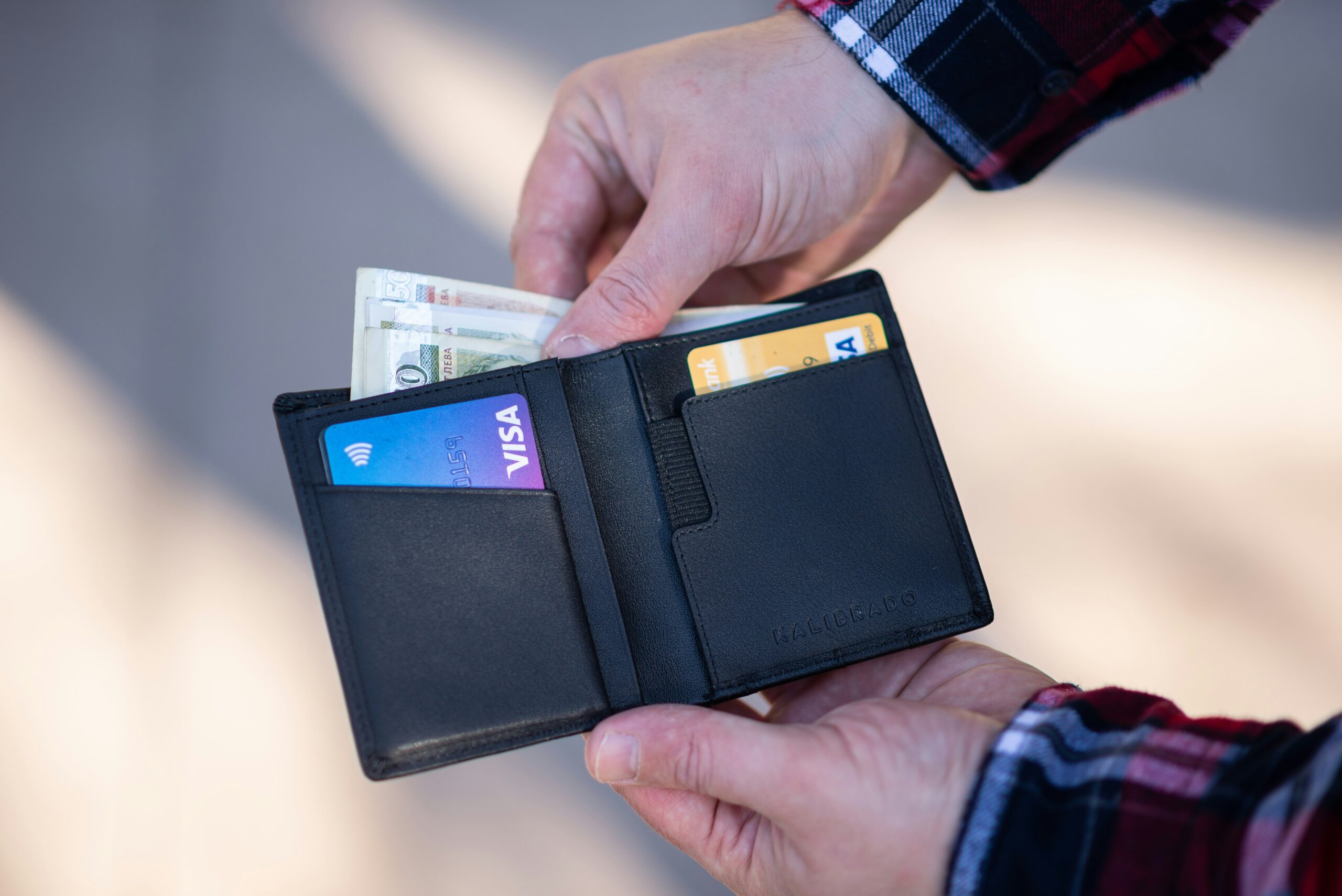 Person opening a wallet showing empty or low cash